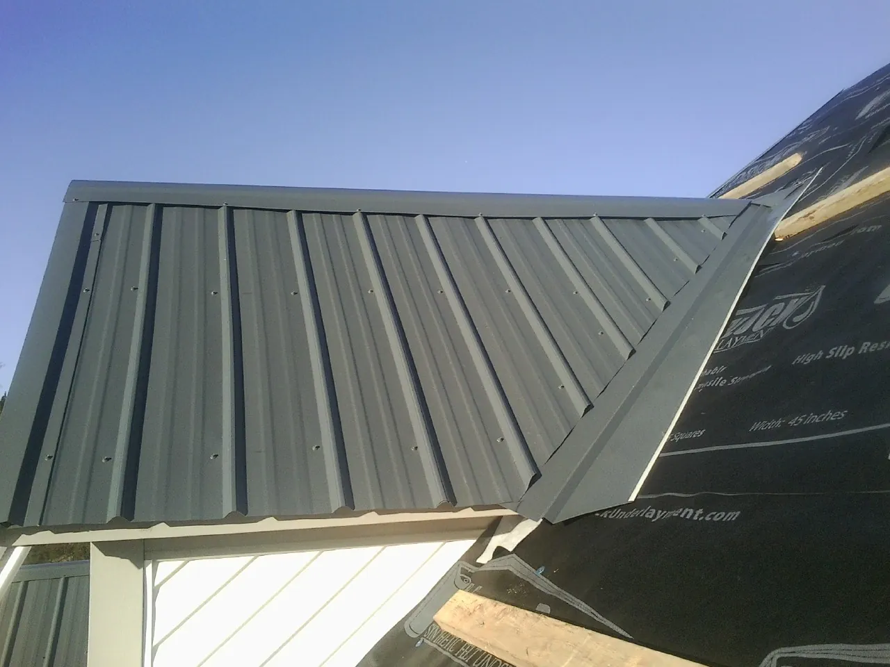 Gray metal roof panels going on over a garage gable in Braidwood