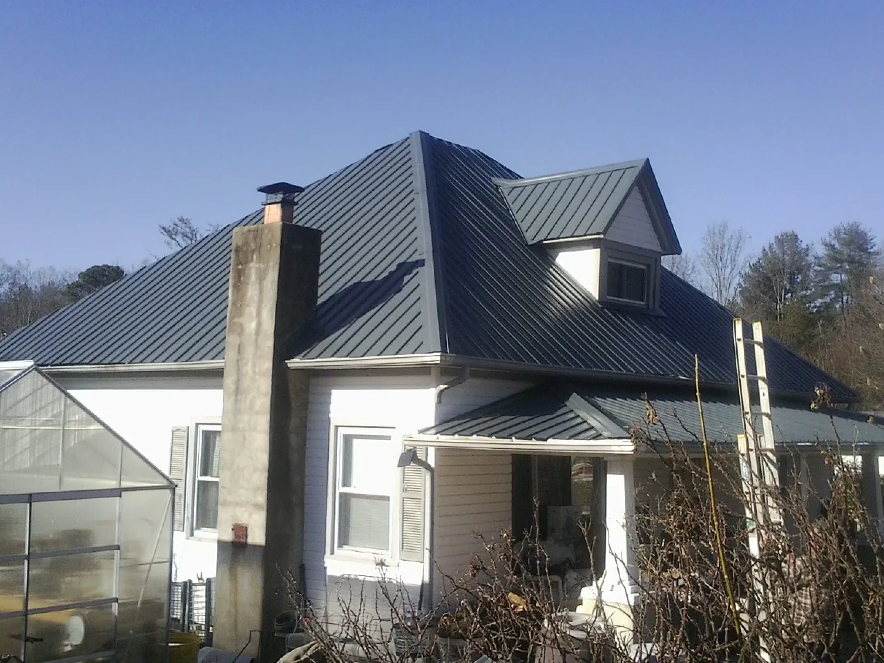 Dark blue standing seam metal roof on a white farmhouse with dormer — Slate & Tile Roof Repair by Roofing Brothers in Braidwood