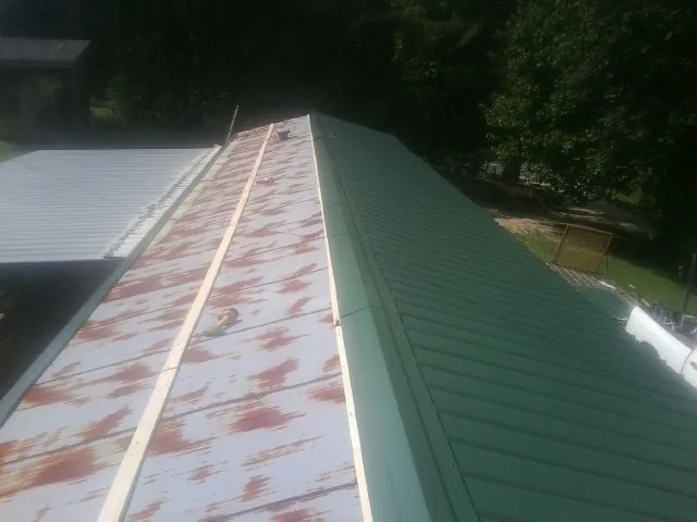 Old rusted panels beside newly installed green metal roofing — Wind Damage Roof Repair by Roofing Brothers in Braidwood