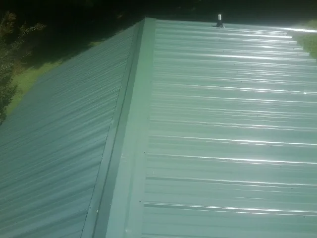 New green metal panels meeting at the ridge of a roof — Flat Roof Repair work by our crew in Braidwood