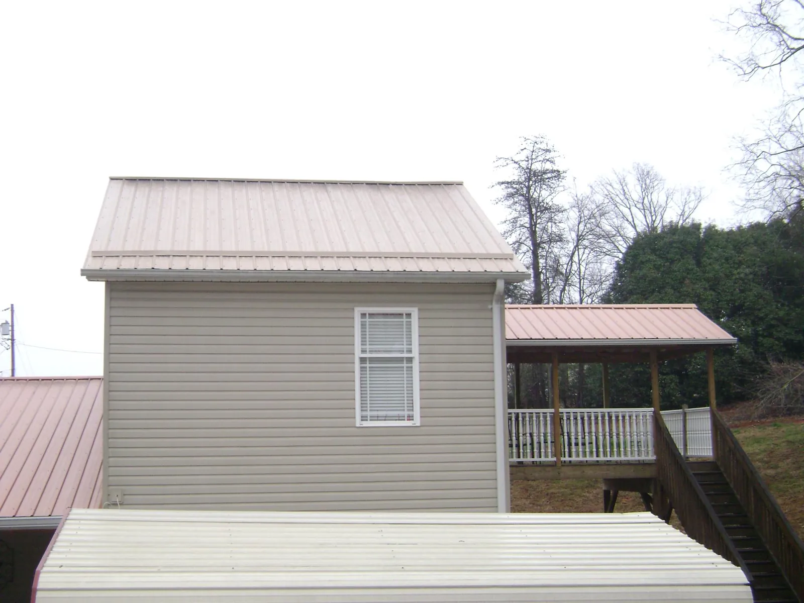 Tan metal roofs on a two story addition and attached porch, from a Roof Replacement job in Braidwood
